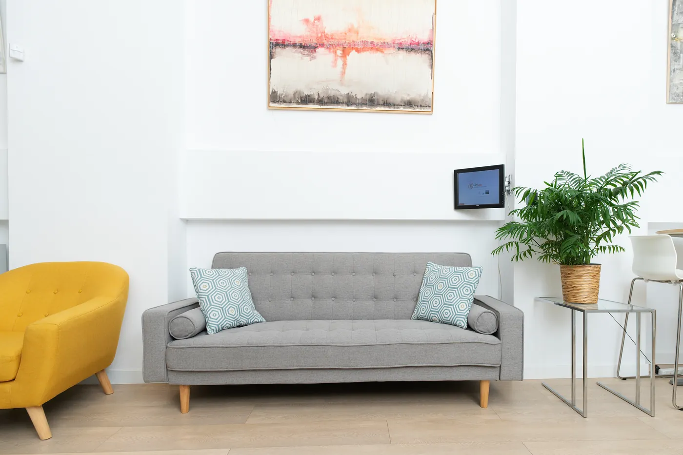 Zona de espera con sofá y sillón amarillo en CN Centros de Negocios